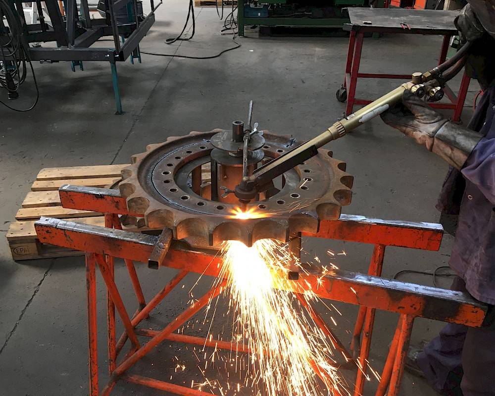 Technician does welding on gear in workshop