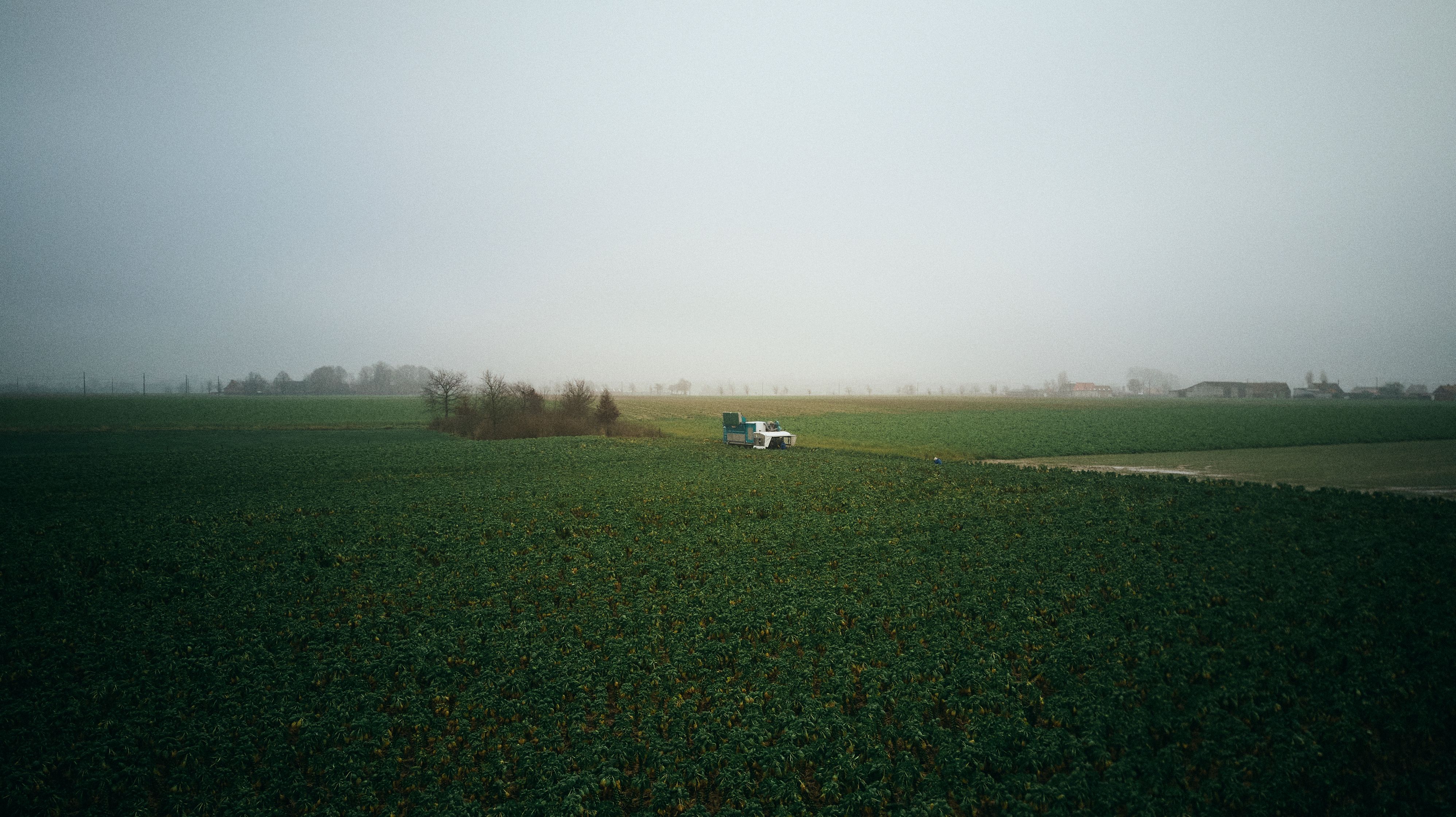 machine agricole dans la campagne, avec des fermes en arrière-plan