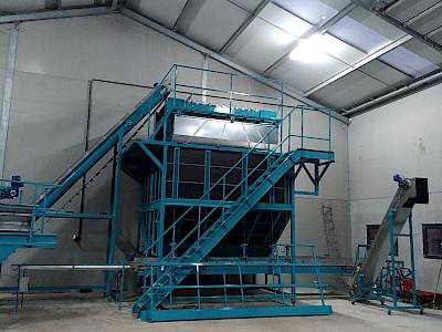 A blue bunker used for storing vegetables with stairs and a conveyor belt