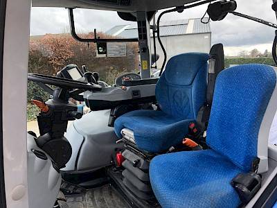 De binnenkant van de cabine van een NEW HOLLAND T7.250, met het stuur en twee blauwe stoelen