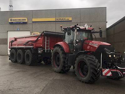 red tractor with red trailer with Deman hydraulic arm system