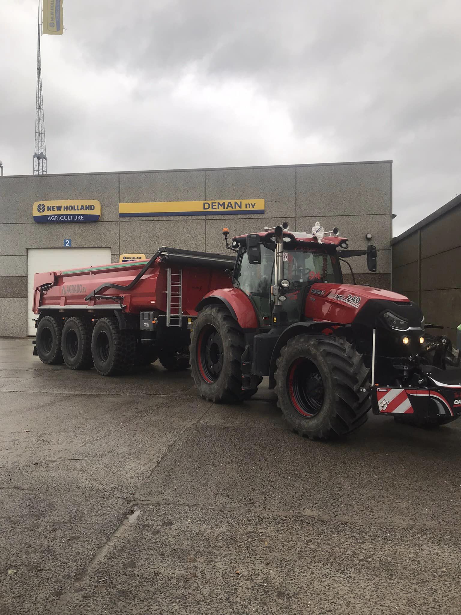 red tractor with red trailer with Deman hydraulic arm system